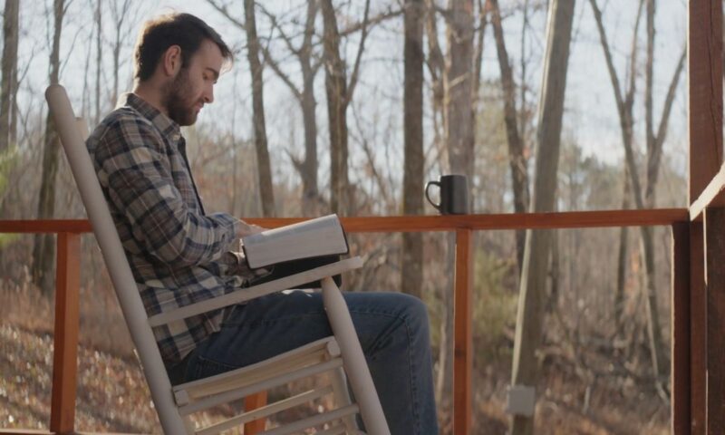 momak sedi na terasi i čita knjigu