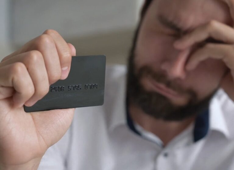 momak plače i drži svoju kreditnu karticu u ruci
