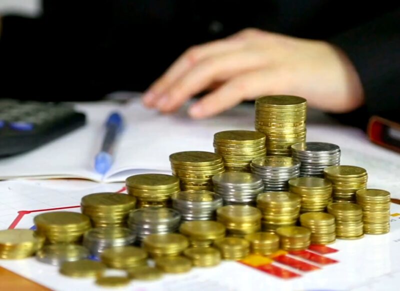 ženska osoba sedi pored mnogo kovanica novca