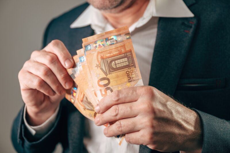 prikaz muške osobe koja drži novčanice od 50e u ruci
