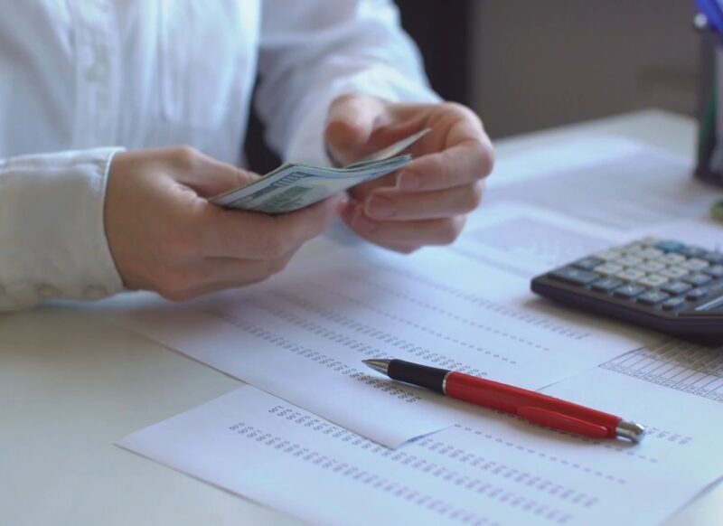 osoba broji novac i zapisuje finansijski plan