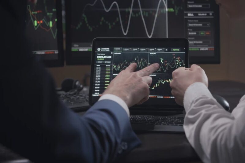 prikaz dve osobe koje prate tokove investiranja na laptopu