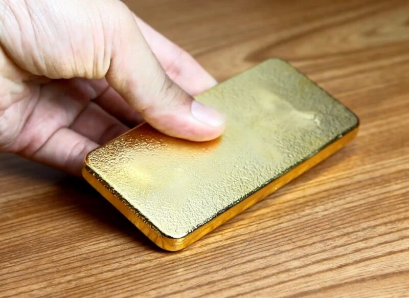 osoba drži zlatnu polugu u ruci