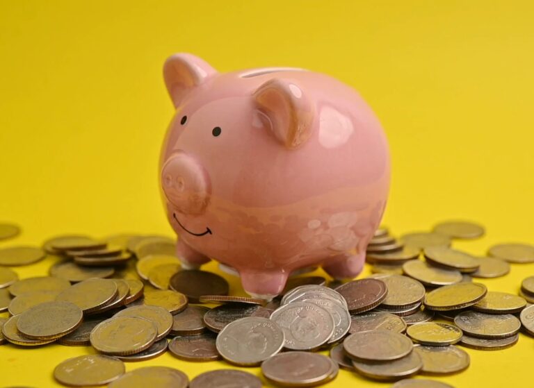 prikaz kasice prasice sa novčićima pored na žutoj pozadini