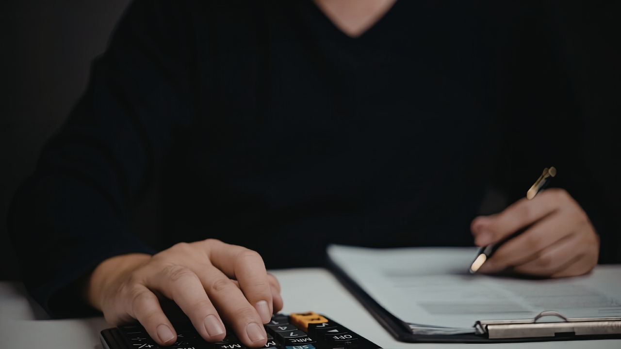 Osoba računa troškove na kalkulatoru dok pregleda dokumenta